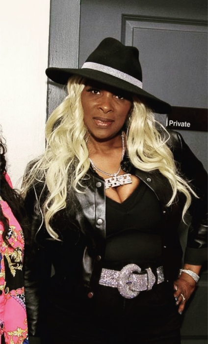 Tre’Jae backstage in a black outfit and statement hat